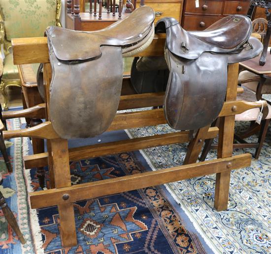 A Victorian saddle stand with two leather saddles W.148cm